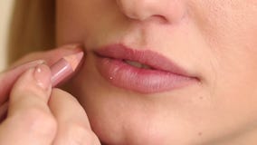 De grimeur schildert de lippen van jong meisje stock footage De grimeur schildert de lippen van jong meisje stock footage