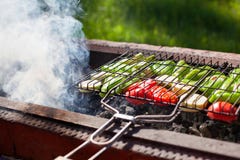 De groenten roosterden bij de grill op houtskool, rook van brand, aard, groene grasachtergrond, groene paprika's, courgette, rode royalty-vrije stock foto De groenten roosterden bij de grill op houtskool, rook van brand, aard, groene grasachtergrond, groene paprika's, courgette, rode royalty-vrije stock foto