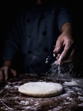 De hand die van de gebakjechef-kok witte bloem over Ruw Deeg op kitche bestrooien stock foto's De hand die van de gebakjechef-kok witte bloem over Ruw Deeg op kitche bestrooien stock foto's