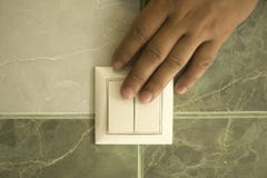 De hand dooft het licht in de badkamers gebruikend een muurschakelaar stock afbeelding De hand dooft het licht in de badkamers gebruikend een muurschakelaar stock afbeelding