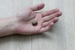 De hand op de vloer in de palm waarvan een patroonhuls, een moord ligt royalty-vrije stock fotografie De hand op de vloer in de palm waarvan een patroonhuls, een moord ligt royalty-vrije stock fotografie