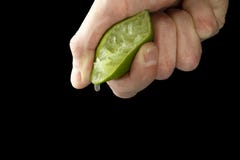 De hand van een mens drukt sap van de helft van een kalk Sappige daling die neer hangen stock foto De hand van een mens drukt sap van de helft van een kalk Sappige daling die neer hangen stock foto