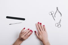 De handen van vrouwen met een rode manicureschaar en een nagelvijl op een wh royalty-vrije stock afbeeldingen De handen van vrouwen met een rode manicureschaar en een nagelvijl op een wh royalty-vrije stock afbeeldingen