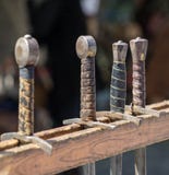 De handvatten van historische zwaarden hingen op een rij op een middeleeuwse markt royalty-vrije stock foto's De handvatten van historische zwaarden hingen op een rij op een middeleeuwse markt royalty-vrije stock foto's