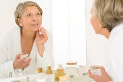 De hogere vrouw bekijkt zich badkamersspiegel stock afbeeldingen De hogere vrouw bekijkt zich badkamersspiegel stock afbeeldingen