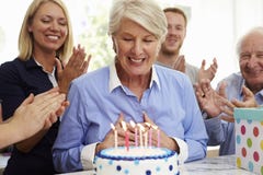 De hogere Vrouw blaast uit de Kaarsen van de Verjaardagscake bij Familiepartij stock afbeeldingen De hogere Vrouw blaast uit de Kaarsen van de Verjaardagscake bij Familiepartij stock afbeeldingen