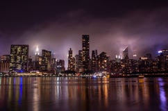 De horizon van Manhattan bij nacht met bezinningen, NYC, de V.S. stock afbeelding De horizon van Manhattan bij nacht met bezinningen, NYC, de V.S. stock afbeelding
