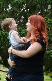 De houdende van zoon die van de de peuterbaby van de moederholding samen in openlucht lachen stock foto De houdende van zoon die van de de peuterbaby van de moederholding samen in openlucht lachen stock foto