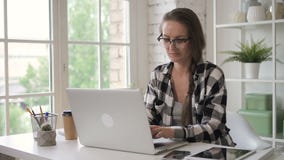 De jonge bedrijfseigenaaronderneemster werkt met laptop, zittend in de ruimte van het huisbureau stock videobeelden De jonge bedrijfseigenaaronderneemster werkt met laptop, zittend in de ruimte van het huisbureau stock videobeelden