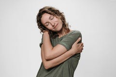 De jonge krullende vrouw die koesteren, kijkt gelukkig, houdt zich van, heeft hoge zelfachting stock afbeelding De jonge krullende vrouw die koesteren, kijkt gelukkig, houdt zich van, heeft hoge zelfachting stock afbeelding
