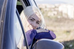 De jonge mooie jonge auto die van de vrouwenzitting uit open venster kijken stock fotografie De jonge mooie jonge auto die van de vrouwenzitting uit open venster kijken stock fotografie
