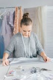 De jonge naaister maakt kleren snijdend stof stock foto De jonge naaister maakt kleren snijdend stof stock foto