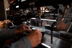De jonge professionele baristamens bereidt heerlijke hete koffie in een moderne koffiemachine voor royalty-vrije stock foto's De jonge professionele baristamens bereidt heerlijke hete koffie in een moderne koffiemachine voor royalty-vrije stock foto's
