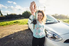 De jonge sleutels van de vrouwenholding tot nieuwe auto en het glimlachen bij camera stock afbeelding De jonge sleutels van de vrouwenholding tot nieuwe auto en het glimlachen bij camera stock afbeelding