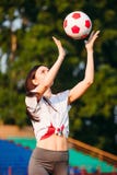 De jonge sportieve vrouw werpt op voetbalbal stock afbeelding De jonge sportieve vrouw werpt op voetbalbal stock afbeelding