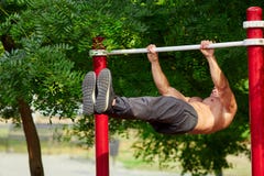 De jonge sterke mens doet trekkracht-UPS op een rekstok op een sportengrond in de zomer in de stad stock afbeeldingen De jonge sterke mens doet trekkracht-UPS op een rekstok op een sportengrond in de zomer in de stad stock afbeeldingen