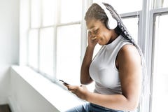 De jonge tiener mooie Afrikaanse Amerikaanse vrouw geniet van luister aan muziek met hoofdtelefoons stock foto's De jonge tiener mooie Afrikaanse Amerikaanse vrouw geniet van luister aan muziek met hoofdtelefoons stock foto's
