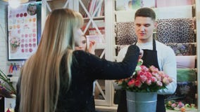 De jonge vrolijke man en de mooie vrouwenbloemisten spreken aan klant en geven advies stock footage De jonge vrolijke man en de mooie vrouwenbloemisten spreken aan klant en geven advies stock footage