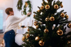 De jonge vrouw verfraait de Kerstmisboom creërend de vakantieatmosfeer Stock Afbeeldingen De jonge vrouw verfraait de Kerstmisboom creërend de vakantieatmosfeer Stock Afbeeldingen