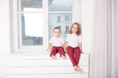 De jongen en het meisje zijn broer en de zuster zit op de vensterbank bij het venster royalty-vrije stock foto's De jongen en het meisje zijn broer en de zuster zit op de vensterbank bij het venster royalty-vrije stock foto's