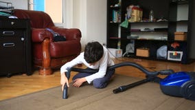 De jongen maakt het tapijt in de ruimte met een stofzuiger schoon stock videobeelden De jongen maakt het tapijt in de ruimte met een stofzuiger schoon stock videobeelden