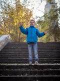 De jongen werpt de bladeren op de stappen in de herfstpark royalty-vrije stock foto De jongen werpt de bladeren op de stappen in de herfstpark royalty-vrije stock foto
