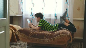 De jongenstiener ligt spelend op tabletspel doorbladerend Internet stock video De jongenstiener ligt spelend op tabletspel doorbladerend Internet stock video