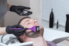 De kapper schildert de baard en de snor van de jonge man in de herenkapper royalty-vrije stock afbeelding De kapper schildert de baard en de snor van de jonge man in de herenkapper royalty-vrije stock afbeelding