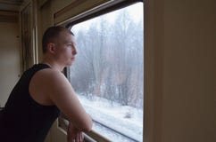 De Kaukasische jonge mens bevindt zich door het venster in een treinauto en bekijkt het venster op een de winter snow-covered lan royalty-vrije stock foto's De Kaukasische jonge mens bevindt zich door het venster in een treinauto en bekijkt het venster op een de winter snow-covered lan royalty-vrije stock foto's