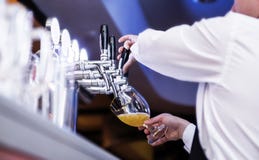 De kelner giet bier in een glas royalty-vrije stock foto De kelner giet bier in een glas royalty-vrije stock foto