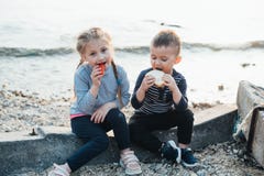 De kinderen van het overzees eten het van de tomatenmeisje en jongen geroosterde brood royalty-vrije stock foto's De kinderen van het overzees eten het van de tomatenmeisje en jongen geroosterde brood royalty-vrije stock foto's