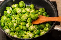 De kleine groene kolen van Spruitjes worden bewogen met een spatel in een pan Keuken hoogste plaat en fornuis op stock foto's De kleine groene kolen van Spruitjes worden bewogen met een spatel in een pan Keuken hoogste plaat en fornuis op stock foto's