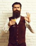 De knappe gebaarde mens met lange baard en snor heeft modieus haar op het ernstige glas van de gezichtsholding van alcoholische d royalty-vrije stock foto De knappe gebaarde mens met lange baard en snor heeft modieus haar op het ernstige glas van de gezichtsholding van alcoholische d royalty-vrije stock foto
