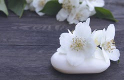 De kosmetische zeep en de witte jasmijnbloemen met groene bladeren liggen op een houten achtergrond Er is een plaats voor uw teks stock afbeeldingen De kosmetische zeep en de witte jasmijnbloemen met groene bladeren liggen op een houten achtergrond Er is een plaats voor uw teks stock afbeeldingen