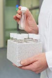 De laboratoriumwetenschapper houdt een plastic doos met de buizen van de glassteekproef royalty-vrije stock foto's De laboratoriumwetenschapper houdt een plastic doos met de buizen van de glassteekproef royalty-vrije stock foto's