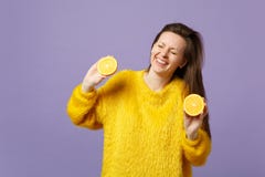 De lachende jonge vrouw in bontsweater die ogen houden sloot, greep halfs van vers rijp oranje fruit dat op violette pastelkleur stock foto's De lachende jonge vrouw in bontsweater die ogen houden sloot, greep halfs van vers rijp oranje fruit dat op violette pastelkleur stock foto's