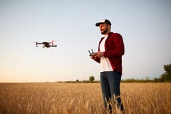 De landbouwer houdt ver controlemechanisme met zijn handen terwijl quadcopter op achtergrond vliegt De hommel hangt achter stock afbeeldingen De landbouwer houdt ver controlemechanisme met zijn handen terwijl quadcopter op achtergrond vliegt De hommel hangt achter stock afbeeldingen