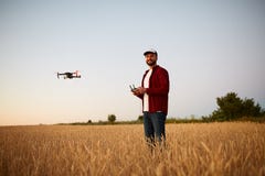 De landbouwer houdt ver controlemechanisme met zijn handen terwijl quadcopter op achtergrond vliegt De hommel hangt achter royalty-vrije stock afbeeldingen De landbouwer houdt ver controlemechanisme met zijn handen terwijl quadcopter op achtergrond vliegt De hommel hangt achter royalty-vrije stock afbeeldingen