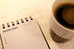 De lege lijst van het vakantieplan in een A5 gerangschikt notitieboekje en koffie stock fotografie De lege lijst van het vakantieplan in een A5 gerangschikt notitieboekje en koffie stock fotografie