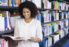 De lezing van de vrouw in een bibliotheek stock afbeeldingen De lezing van de vrouw in een bibliotheek stock afbeeldingen