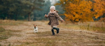 De looppas en de spelen van het kindmeisje met zijn hond tijdens gang royalty-vrije stock fotografie De looppas en de spelen van het kindmeisje met zijn hond tijdens gang royalty-vrije stock fotografie