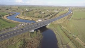 De luchtmening van het vogelsoog van de M7 autosnelweg in Ierland Autosnelweg met brug, rotondes, en beweging stock footage De luchtmening van het vogelsoog van de M7 autosnelweg in Ierland Autosnelweg met brug, rotondes, en beweging stock footage