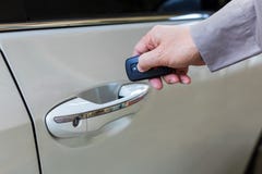 De mannelijke hand opent de witte auto met keyless ingangsfunctie stock fotografie De mannelijke hand opent de witte auto met keyless ingangsfunctie stock fotografie