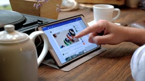 De mens bezoekt facebook website op tabletpc in een koffie stock video De mens bezoekt facebook website op tabletpc in een koffie stock video
