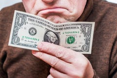 De mens houdt één dollar in zijn hand en drukt ongenoegen bij uit royalty-vrije stock foto De mens houdt één dollar in zijn hand en drukt ongenoegen bij uit royalty-vrije stock foto