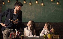De mens met baard onderwijst schoolmeisjes, die boek lezen Nieuwsgierige vrolijke kinderen luisterleraar met aandacht leraar stock afbeeldingen De mens met baard onderwijst schoolmeisjes, die boek lezen Nieuwsgierige vrolijke kinderen luisterleraar met aandacht leraar stock afbeeldingen