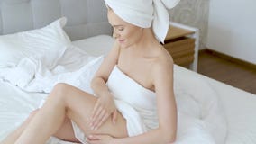De midden oude mooie blonde vrouw bevochtigt benen na de douche stock footage De midden oude mooie blonde vrouw bevochtigt benen na de douche stock footage