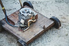 De modieuze oude grasmaaimachine die van DIY zich op een zand behandelde grond bevinden royalty-vrije stock foto De modieuze oude grasmaaimachine die van DIY zich op een zand behandelde grond bevinden royalty-vrije stock foto