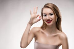De mooie blonde rode lippen die meisje glimlachen toont het teken o.k. stock fotografie De mooie blonde rode lippen die meisje glimlachen toont het teken o.k. stock fotografie