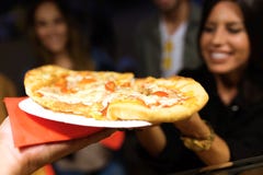 De mooie jonge vrouw en haar vrienden het bezoeken eten markt en het kopen pizza in de straat royalty-vrije stock foto De mooie jonge vrouw en haar vrienden het bezoeken eten markt en het kopen pizza in de straat royalty-vrije stock foto